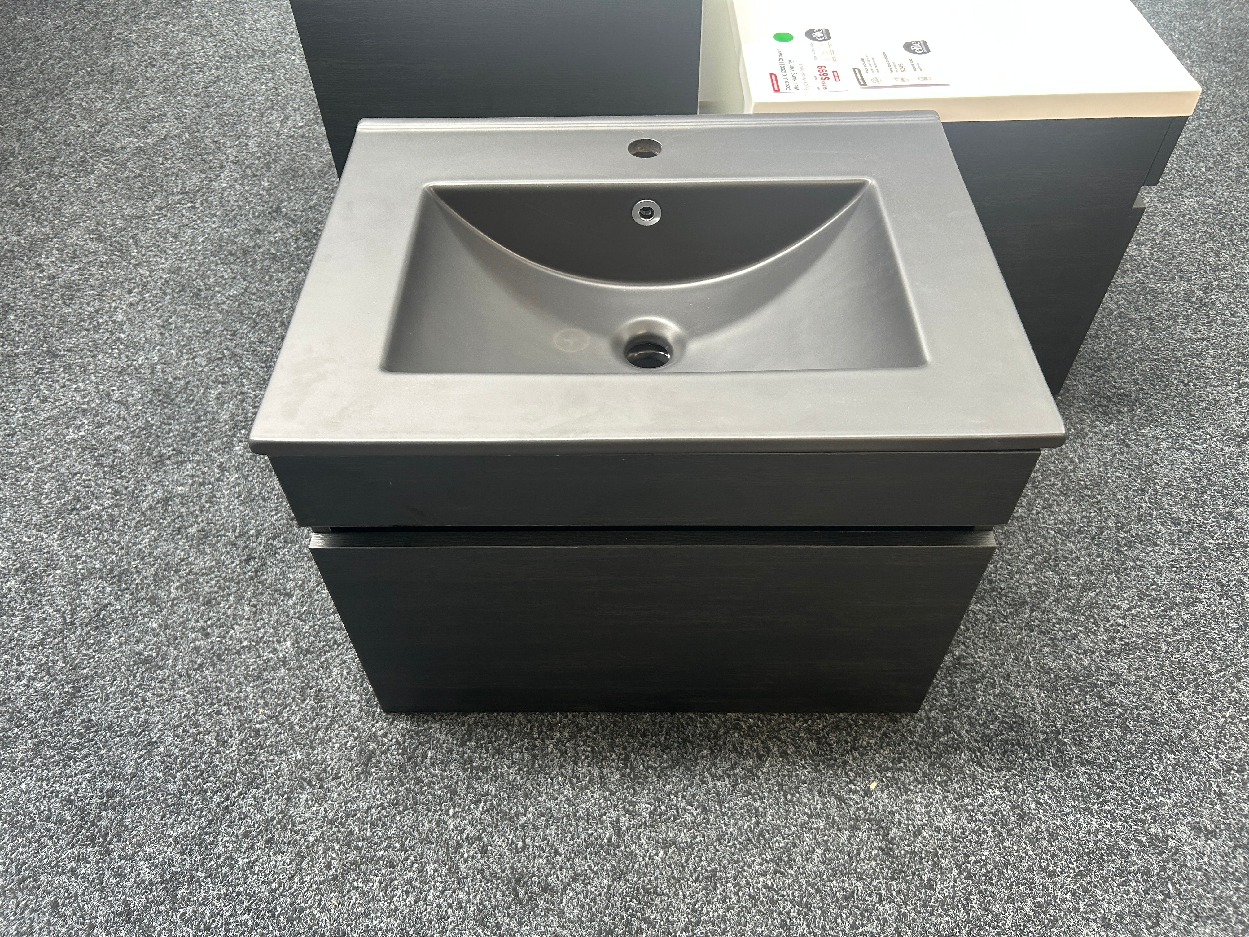 A modern wall-mounted bathroom vanity with a matte black cabinet and a dark gray integrated sink basin clearance sale deal
